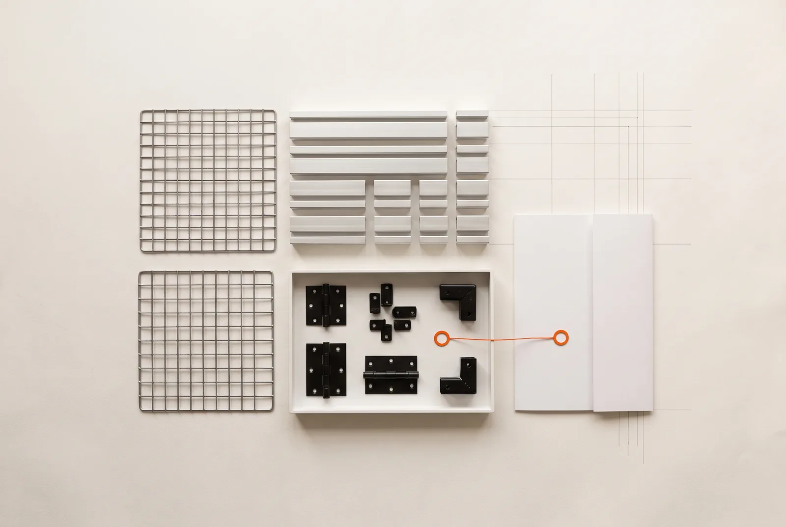 Aufsicht auf hellem Papier: zwei Gitterpaneele, nach Länge sortierte Aluminiumprofile, eine weiße Schale mit schwarzen Scharnieren und Eckverbindern und eine weiße Mappe, verbunden durch eine orange Linie.